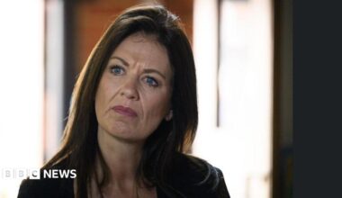 A woman with long brown hair is appearing to be concentrating on something in the room.