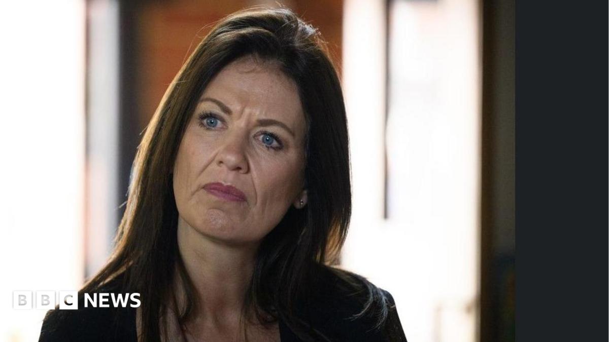 A woman with long brown hair is appearing to be concentrating on something in the room.