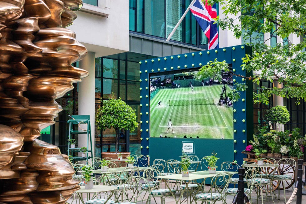 Patio with metal chairs, large screen showing tennis, and decorative sculpture. Patio with metal chairs, large screen showing tennis, and decorative sculpture.