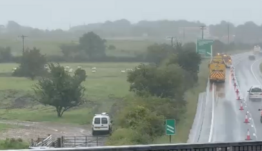Cars drive down the A30 in Devon. One lane is closed off towards the exit slip road at Sourton Cross, near Okehampton. It is wet.