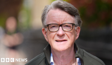 Mandelson pictured walking down a London street. He is dressed casually in a green raincoat and an open necked shirt.