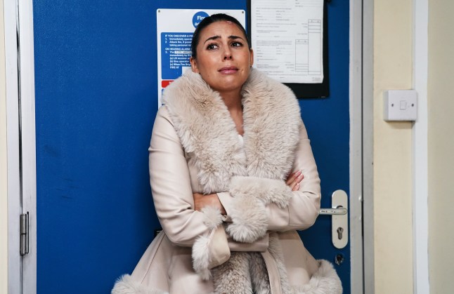 Priya in the car lot office looking upset in EastEnders
