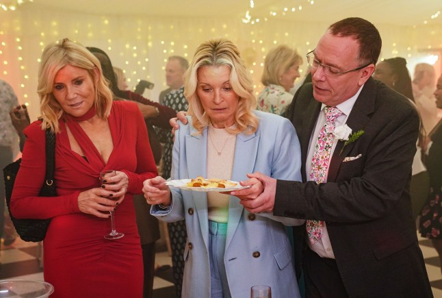 Ian helps Kathy with a sandwich as Cindy watches on in EastEnders