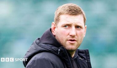Finn Russell standing on the pitch wearing a black coat looking over his right shoulder before Bath v Leicester.