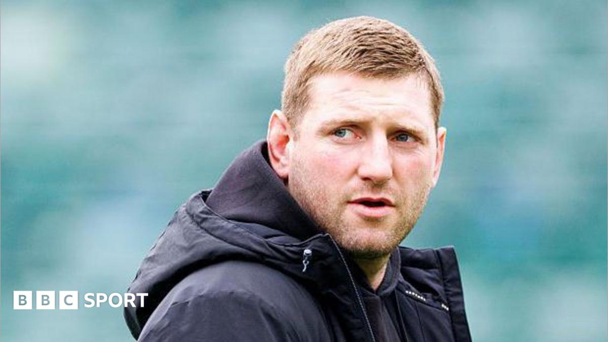 Finn Russell standing on the pitch wearing a black coat looking over his right shoulder before Bath v Leicester.