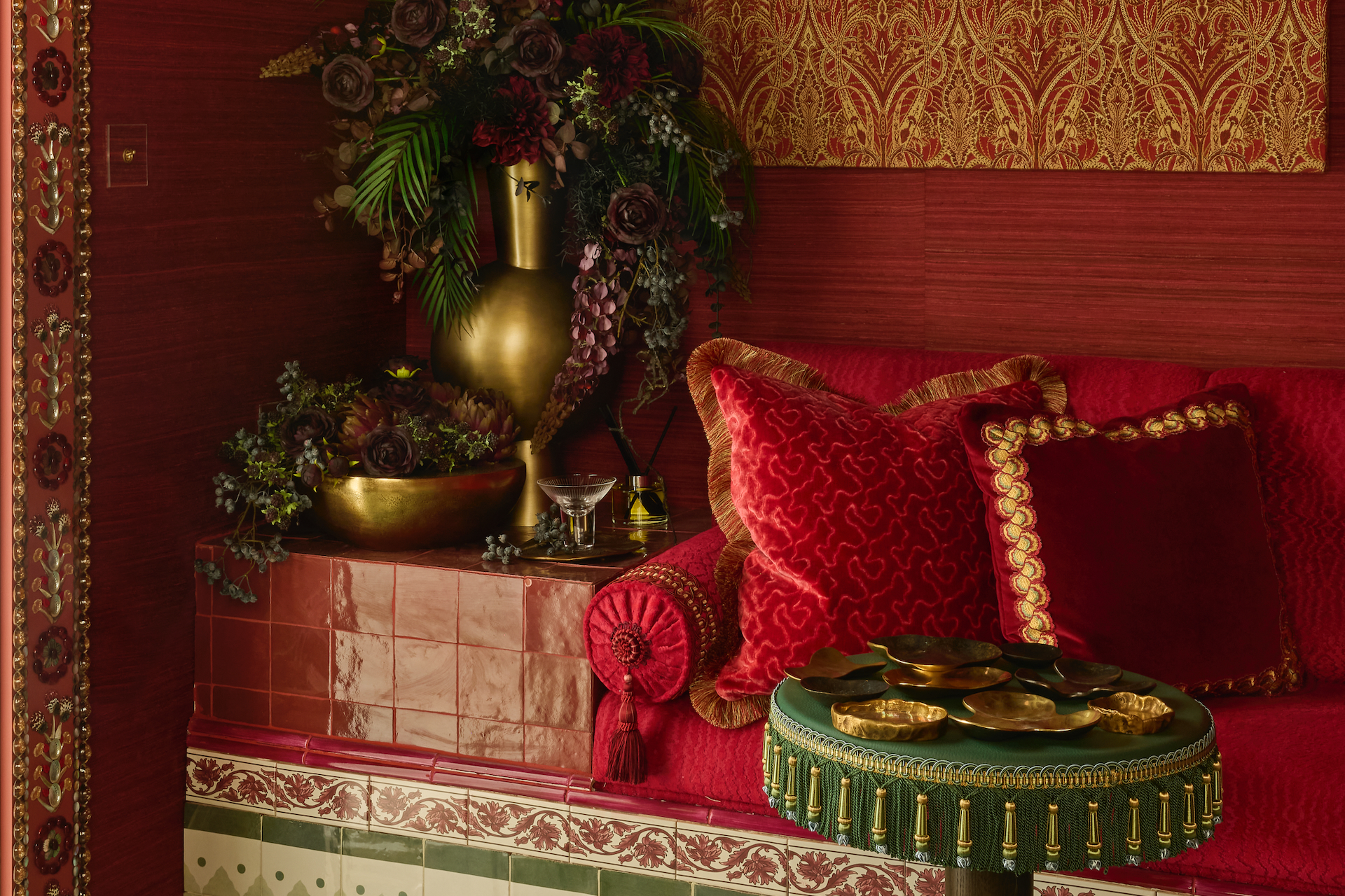 a red room with tiled built in seating, luxurious red and green tassels and textured red walls