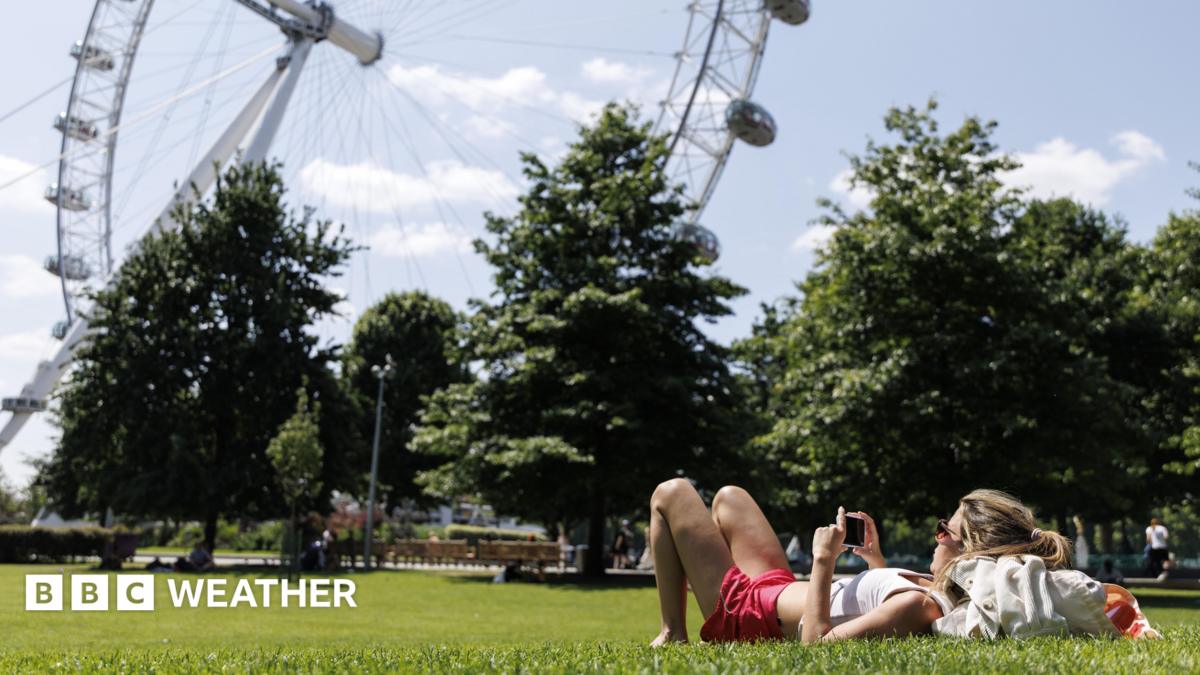 A woman lies in the sun, on the grass, with the London Eye in the background
