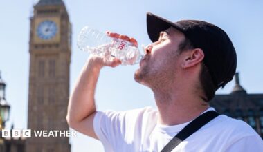 A man drinks from a water bottle with a sunny sky overhead and a blurred view of the Westminster skyline in the background