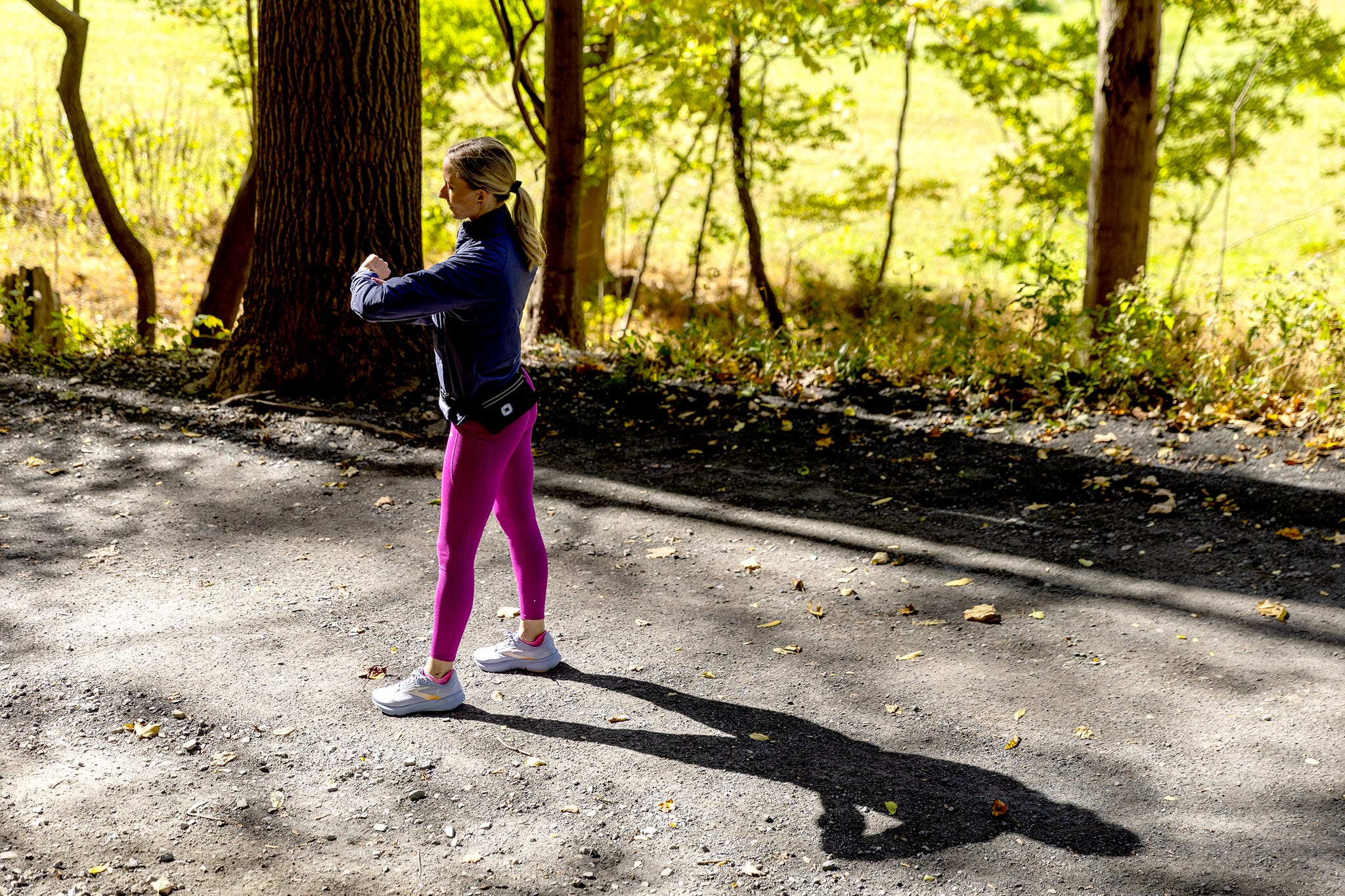 Person exercising outdoors on a path lined with trees.