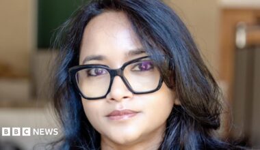 A woman - Prof Ronita Bardhan - looking directly at the camera with a neutral expression. She is wearing black glasses and has dark hair.