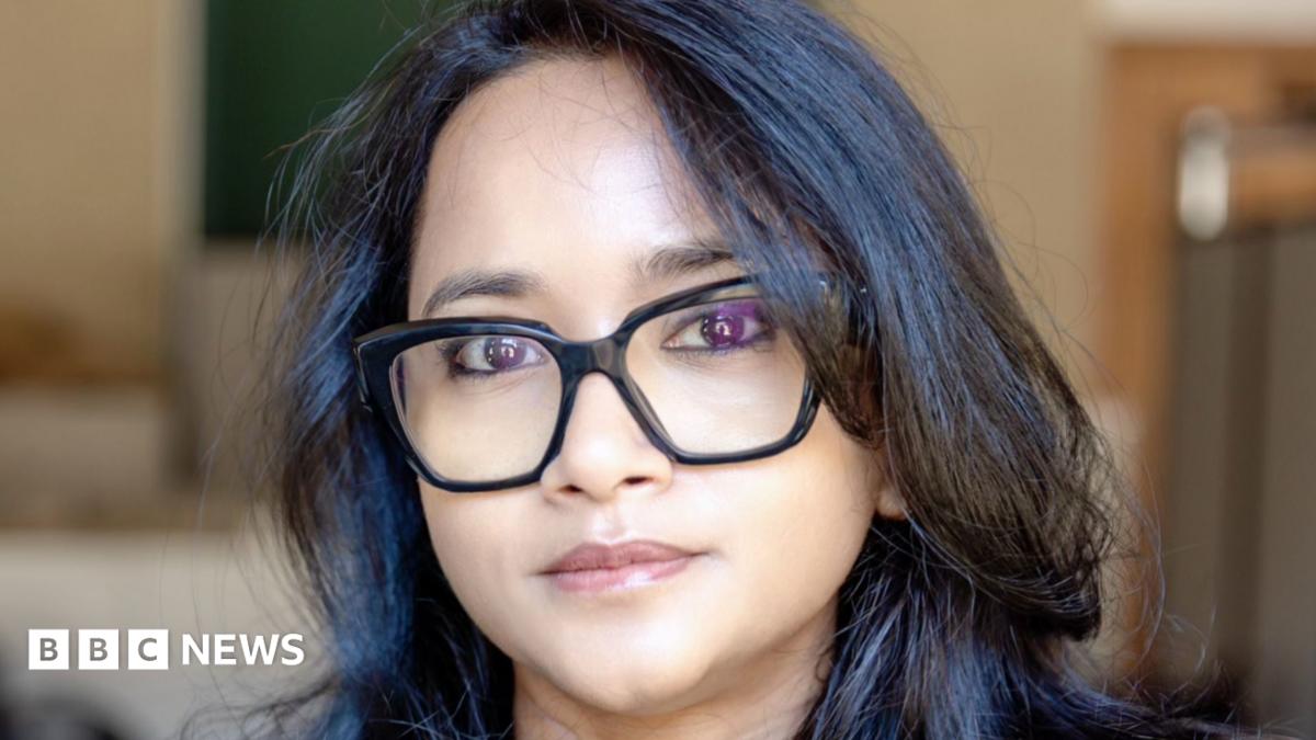 A woman - Prof Ronita Bardhan - looking directly at the camera with a neutral expression. She is wearing black glasses and has dark hair.