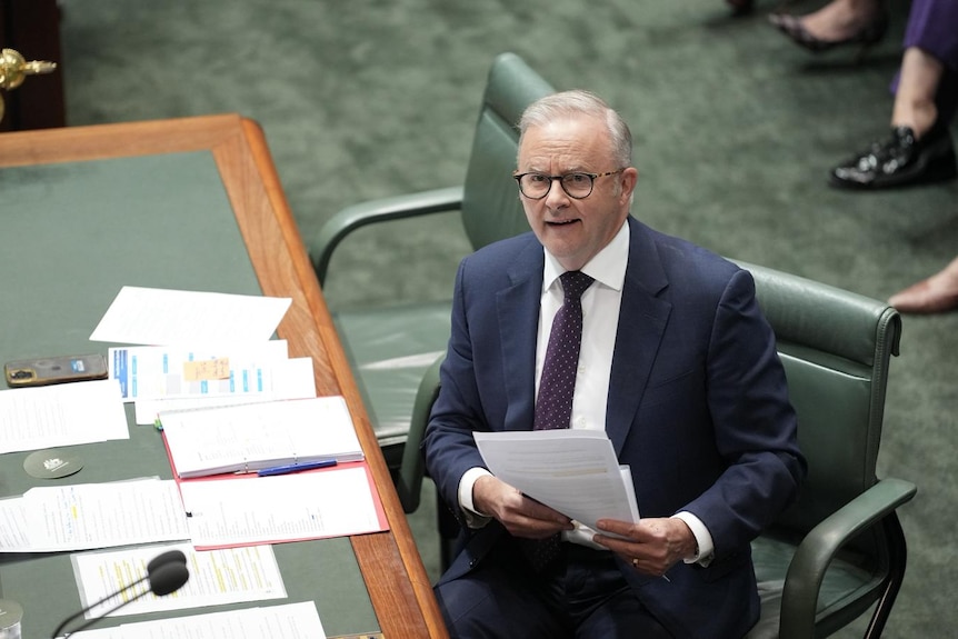 Anthony Albanese sits and holds a piece of paper.
