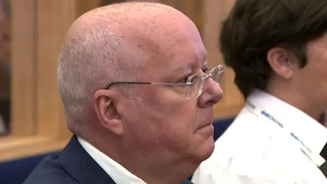 Peter Murrell in the dock, sittign next to a prison guard