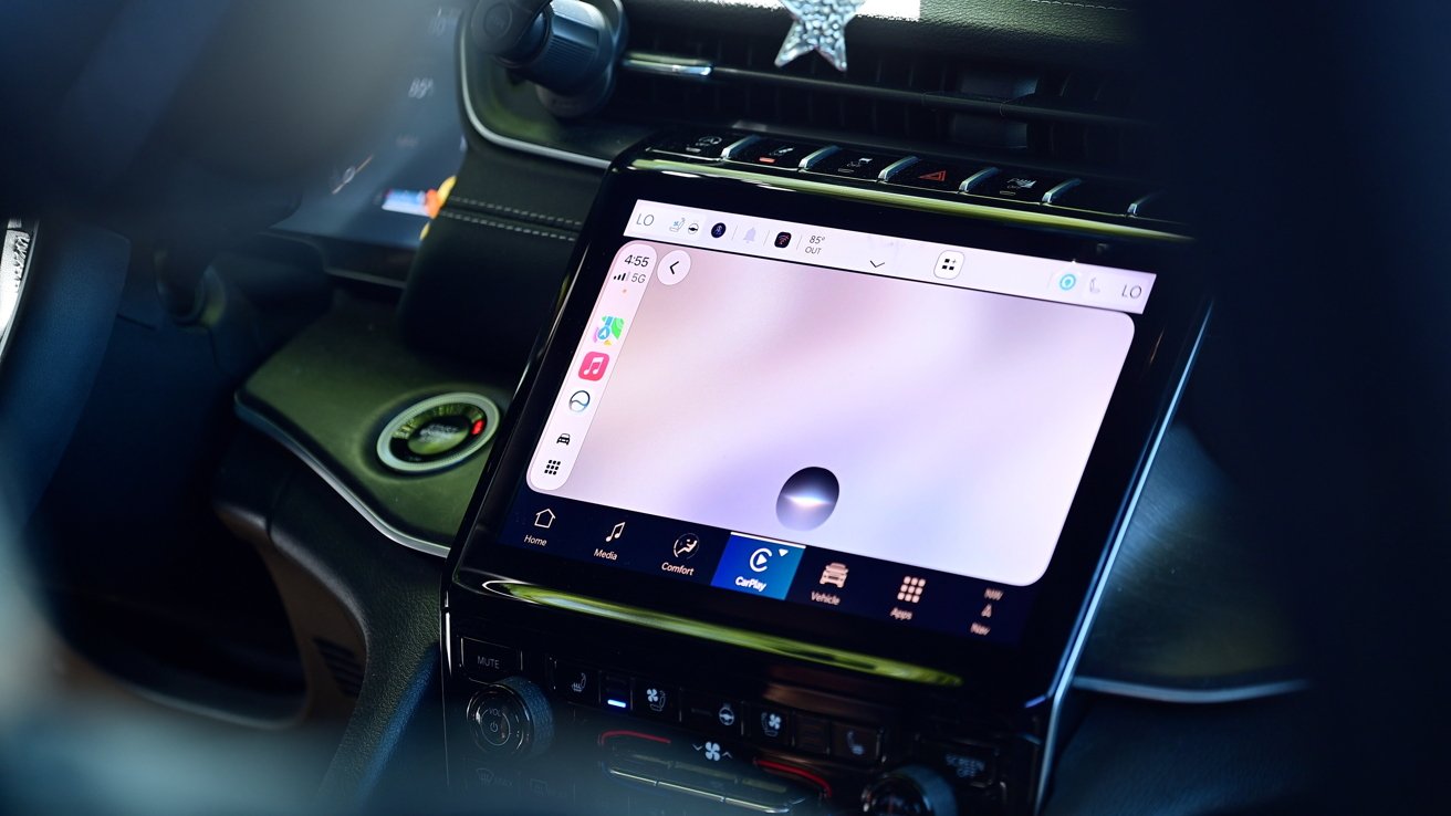 Close-up of a car's center console featuring a large touchscreen infotainment display with navigation and app icons, surrounded by dark dashboard controls and a decorative star hanging above
