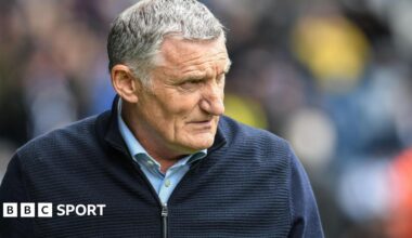 Tony Mowbray wearing a blue cardigan looks to his left