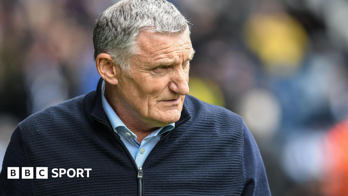 Tony Mowbray wearing a blue cardigan looks to his left