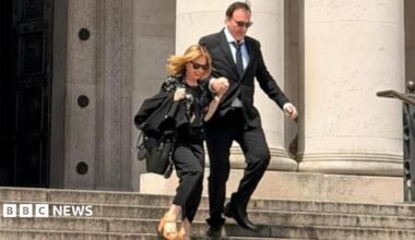 Quentin Tarantino and Kylie Minogue outside National Museum Cardiff. They are walking down the steps outside the museum holding hands. They are both wearing all black outfits and sunglasses. Kylie has a pair of brown tan high heels on.