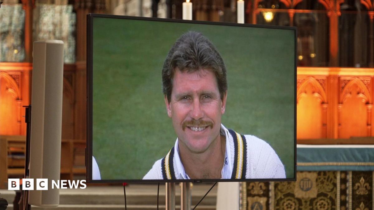 A screen in front of Winchester Cathedral's alter, with a head and shoulders picture of Robin Smith, smiling, in his cricket whites