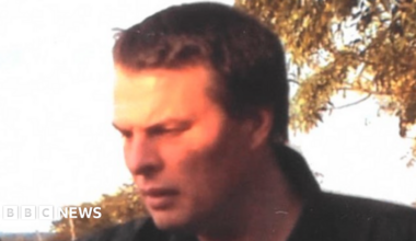 Darren Round pictured with brown hair wearing a blue and white stripe collar T-shirt and dark jacket.