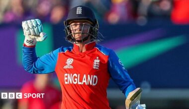 England batter Danni Wyatt-Hodge punches the air in celebration after scoring a century against Sri Lanka. She is wearing red kit, batting gloves and navy blue England helmet.