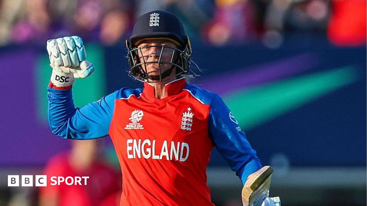 England batter Danni Wyatt-Hodge punches the air in celebration after scoring a century against Sri Lanka. She is wearing red kit, batting gloves and navy blue England helmet.