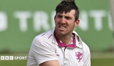 Craig Overton wearing a white Somerset shirt grits teeth