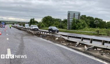 A damaged central reservation with cars driving slowly along one side while the other is completely closed.