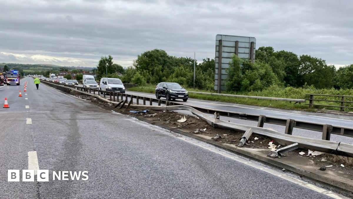 A damaged central reservation with cars driving slowly along one side while the other is completely closed.