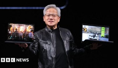 Nvidia's chief executive Jensen Huang holds up two laptop computers on a stage while wearing his trademark black leather jacket.