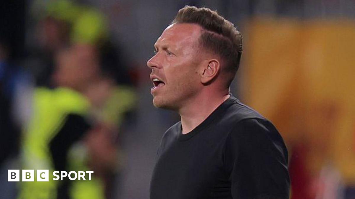 Wales boss Craig Bellamy reacts with an open-mouthed expression as he stands in a round-neck black top