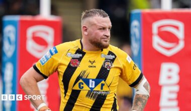 Brad Singleton in a yellow-and-black Castleford shirt with his hands on his hips and the red rugby posts behind him