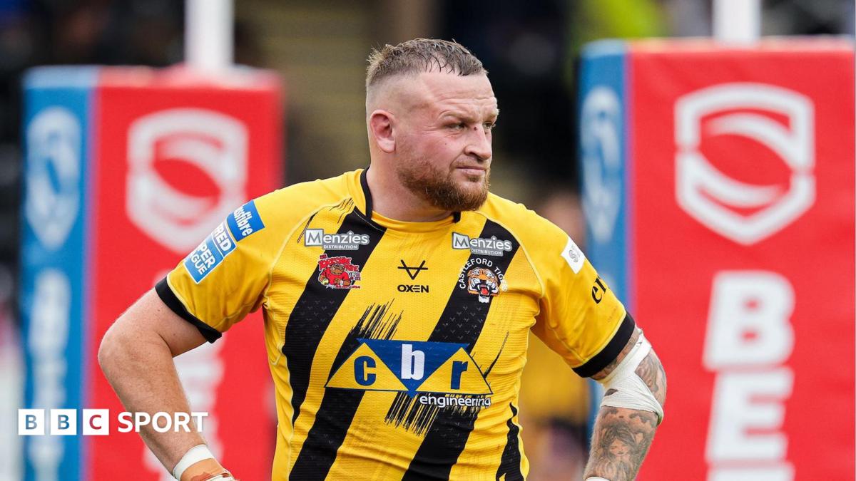 Brad Singleton in a yellow-and-black Castleford shirt with his hands on his hips and the red rugby posts behind him