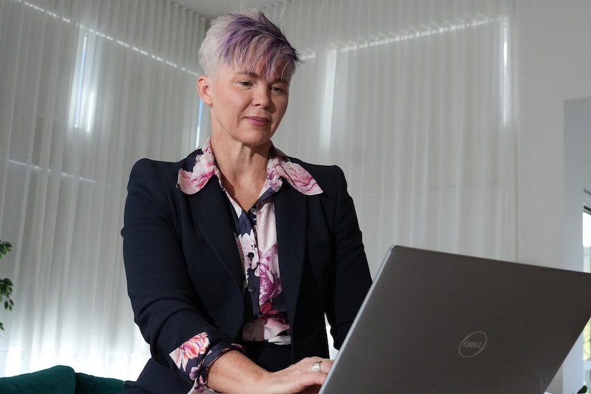 Woman works at a laptop in an office room.