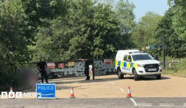 Police car and cones outside lake entrance.