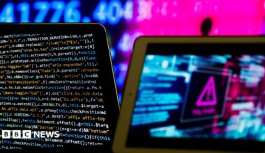 Composite image meant to represent computer software and hardware. On the left is a screen showing code in different colours. There is a pink hazard sign on the right of the picture.