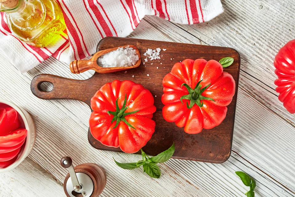 Top view of heirloom tomatoes with olive oil and sea salt on rustic wooden table