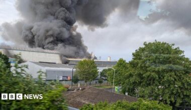 Industrial buildings with large clouds of smoke rising from them into the sky