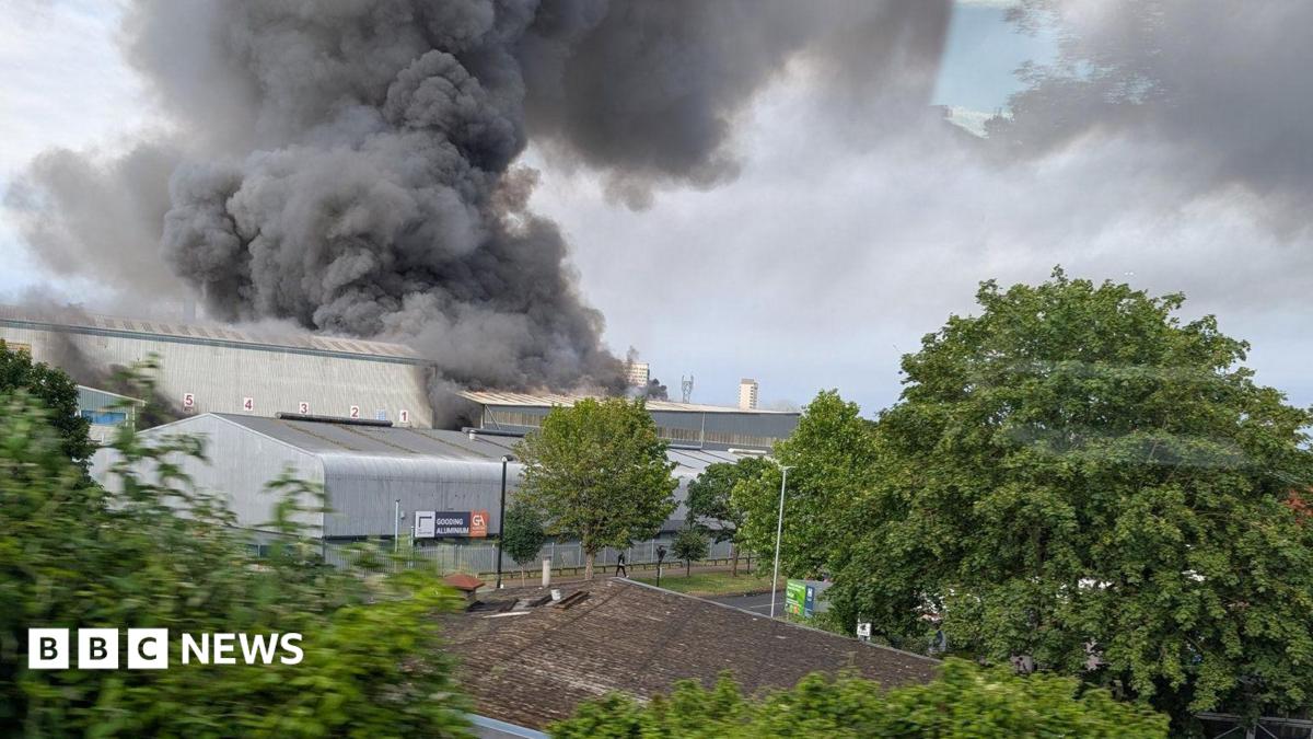 Industrial buildings with large clouds of smoke rising from them into the sky