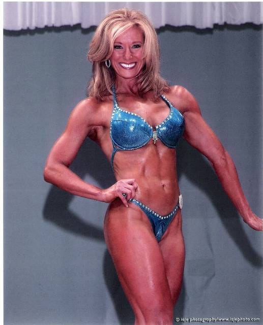 Bodybuilder posing in a blue bikini on stage.