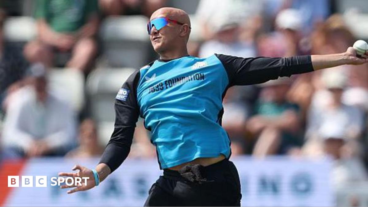 Fateh Singh is about to complete his bowling action in a white-ball game for Worcestershire. He is wearing black trousers and a top with black sleeves and light blue front. He is also wearing sunglasses