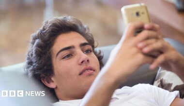 A young man lying on the sofa looking at his phone
