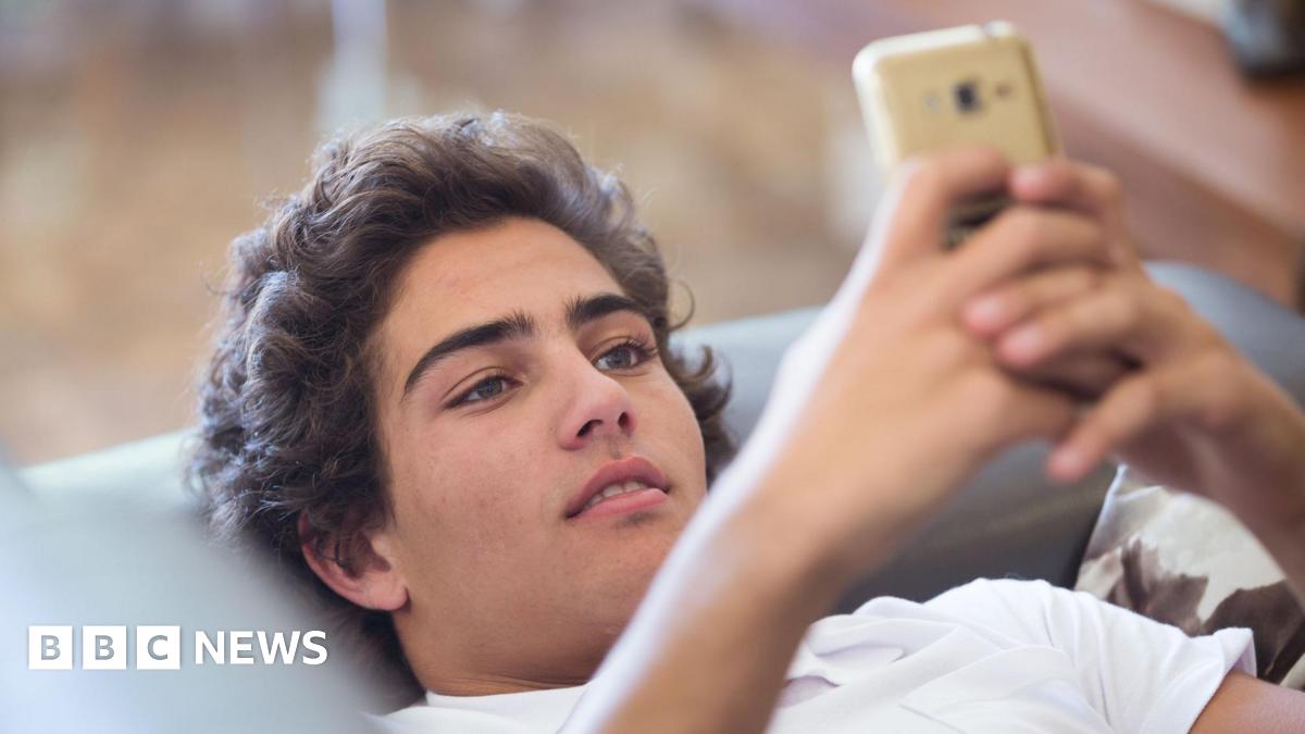 A young man lying on the sofa looking at his phone