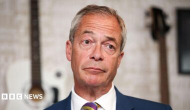 Nigel Farage in a close-up, wearing a blue suit, white shirt and stripe tie.