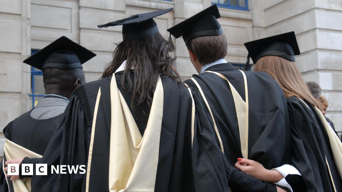 Four students dressed in graduation robes and mortarboards stand with their backs to the camera.