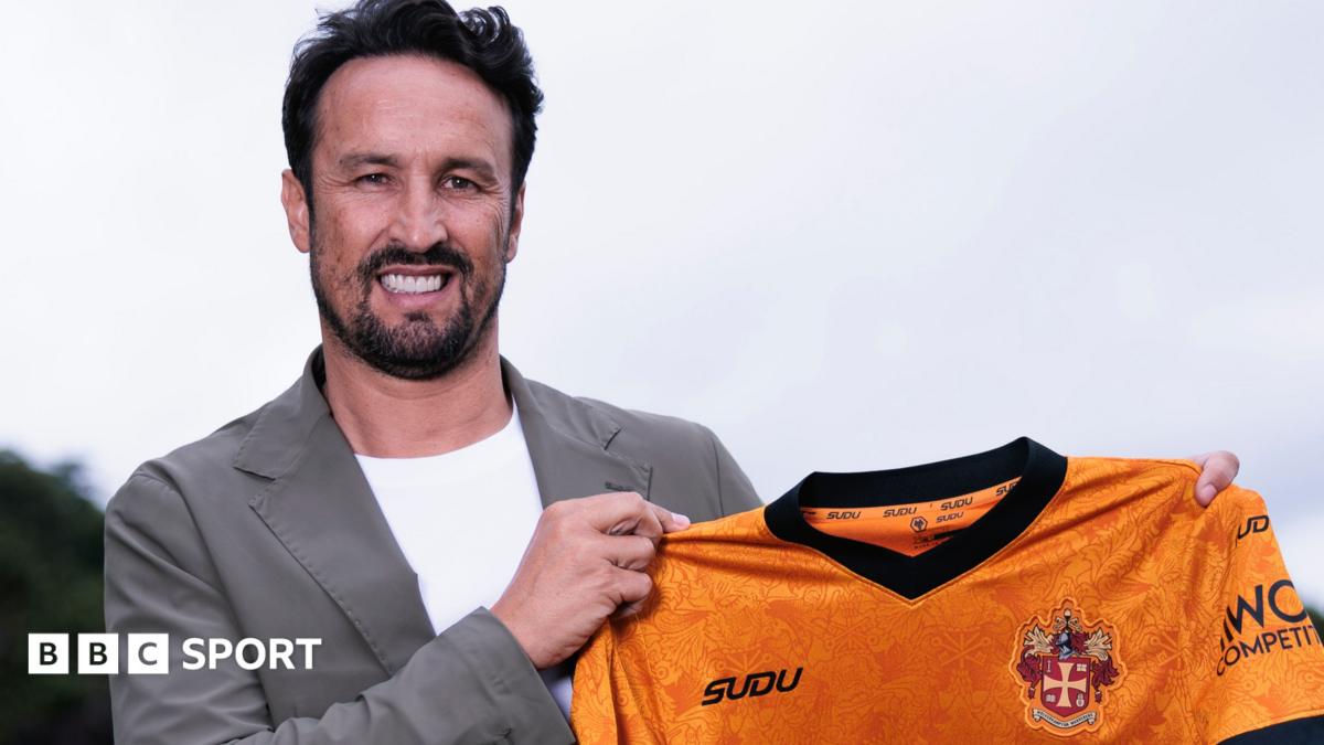 Cesar Peixoto holding a Wolves shirt while smiling