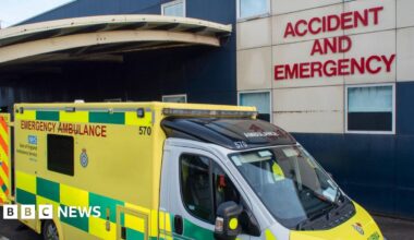 An ambulance parked outside Luton and Dunstable Hospital's Accident and Emergency department. The vehicle is yellow and green.