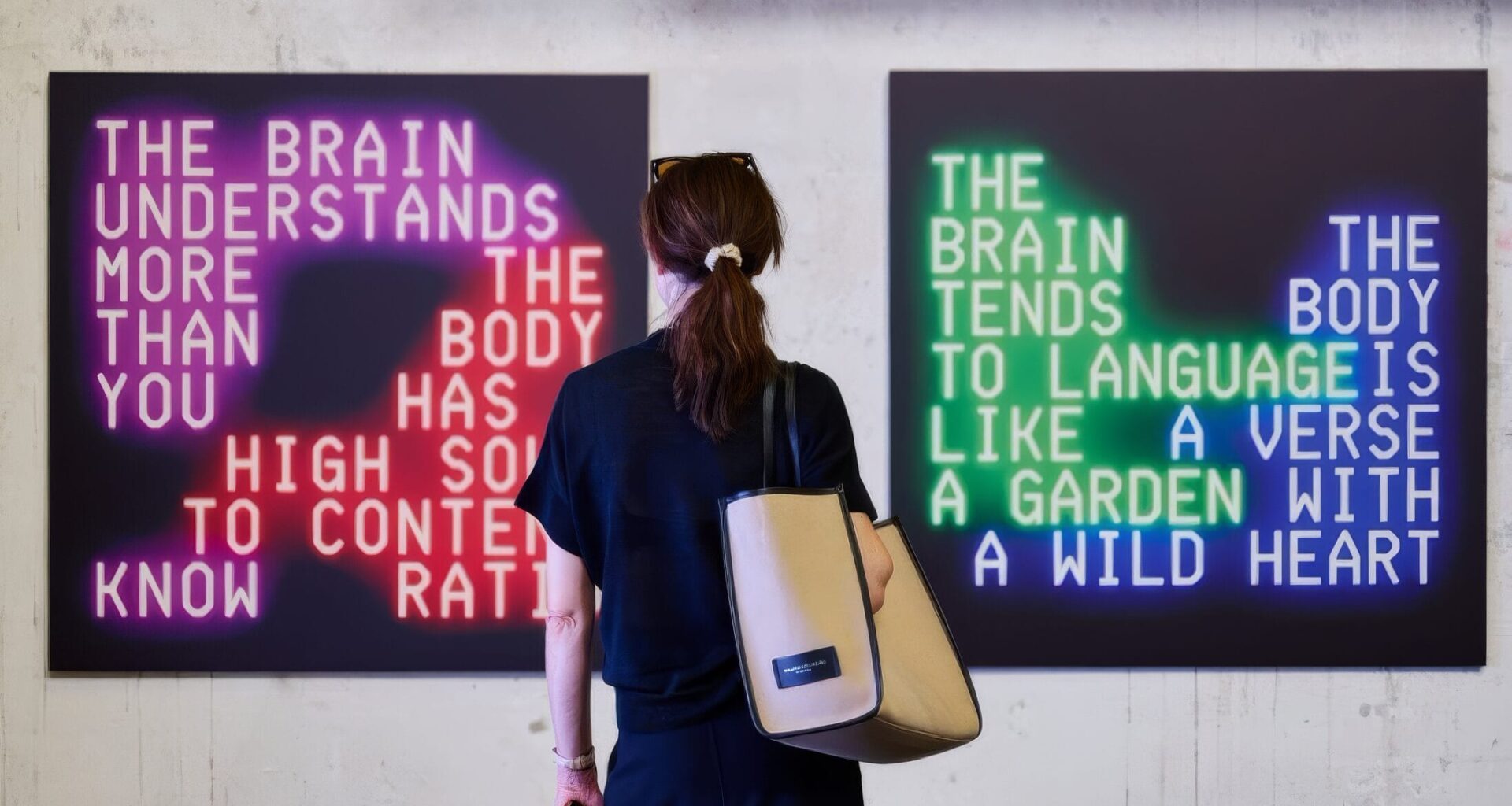 Feminine figure standing in front of two square, text-based artworks.