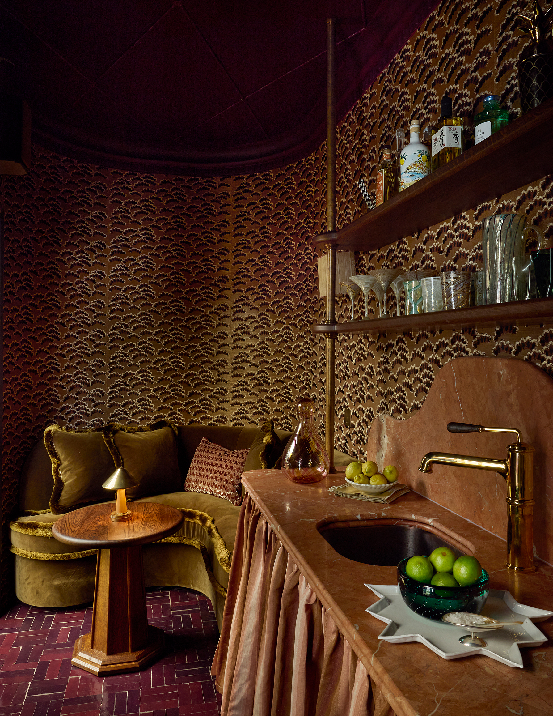 a small curved room with a sink and curved sofa with bold wallpaper and a rich color scheme