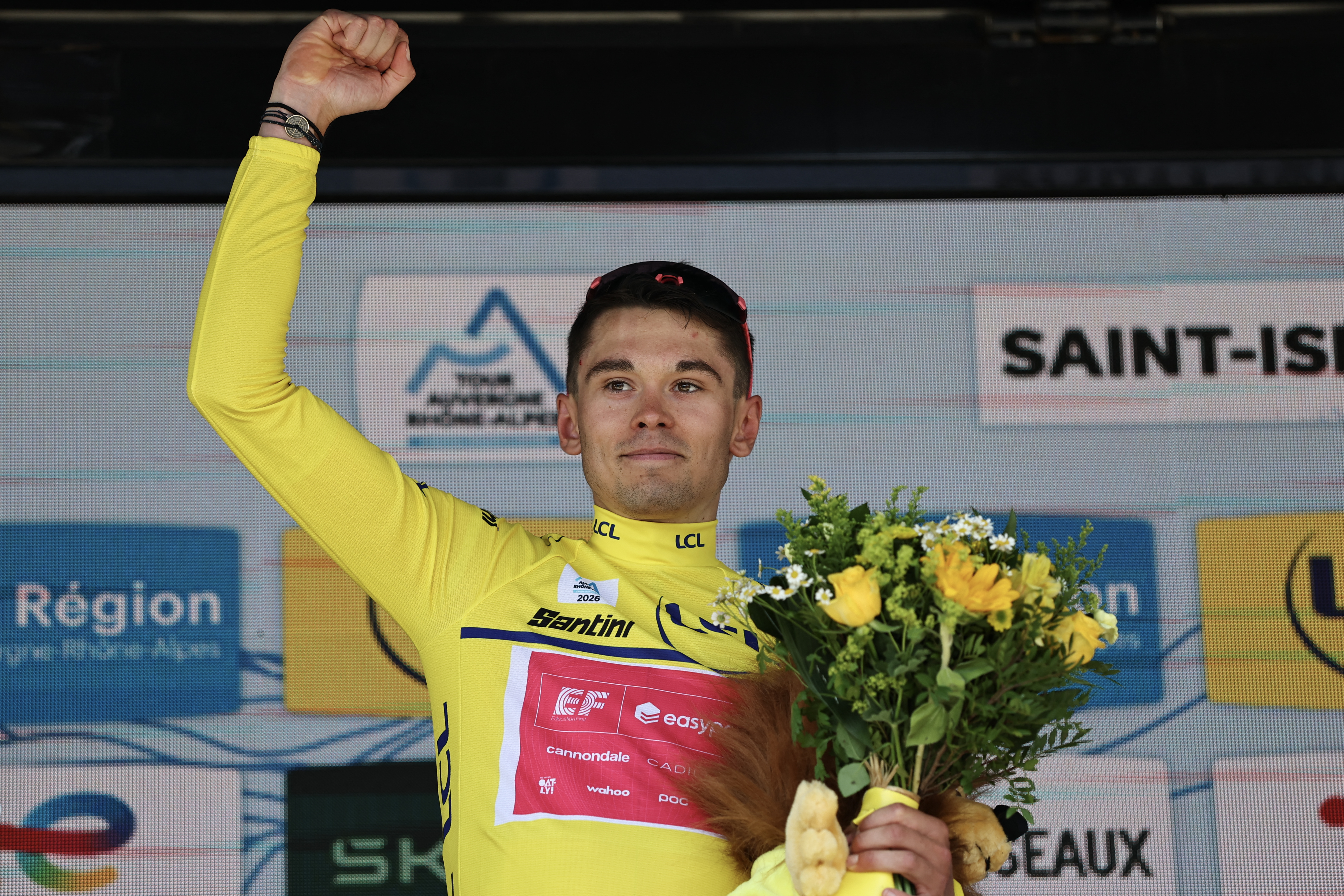 EF Education - EasyPost's French rider Alex Baudin celebrates with the overall leader's yellow jersey on the podium after the 1st stage of the Tour Auvergne-Rhone-Alpes cycling race (formerly known as the Criterium du Dauphine), 146,2km between Vizille and Saint-Ismier, in the French Alps, on June 7, 2026. (Photo by Anne-Christine POUJOULAT / AFP via Getty Images)