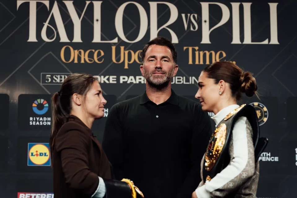 Eddie Hearn Chairman of Matchroom Sport (centre) watches on as Katie Taylor (left) and Flora Pili face off after a press conference ahead of the Katie Taylor v Flora Pili fight at Croke Park on June 5th, 2026 in Dublin, Ireland. (Bran Holloway/Matchroom Boxing)